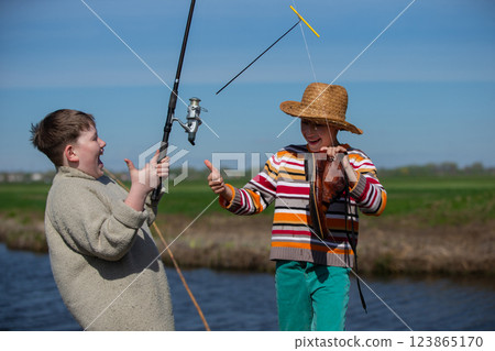 Funny fishing. Two of the boy's friends hooked an old shoe with a fishing rod and are laughing. 123865170
