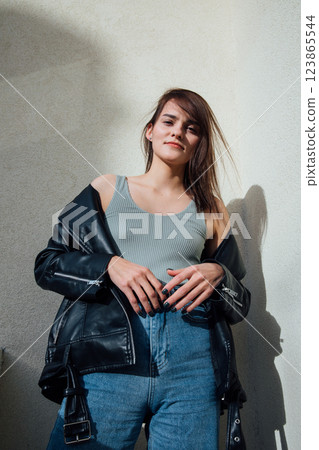 Beautiful slim woman in jeans and black jacket on a set background Beautiful slim woman in jeans and black jacket on a set background 123865544