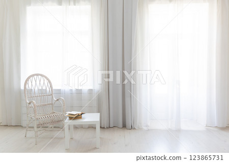 Chair and table with books in the interior of an empty white room with a window Chair and table with books in the interior of an empty white room with a window 123865731