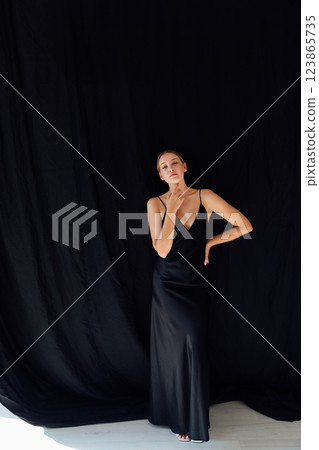 Beautiful slender woman in summer silk dress on black background 123865735