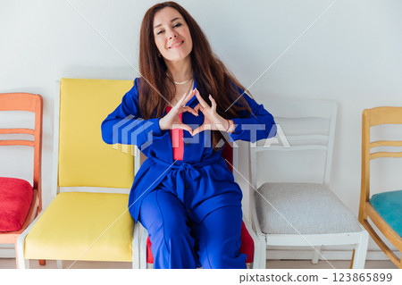 The woman showed with her hands the heart is sitting on chairs 123865899