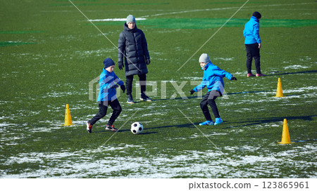 Group of young athletes engaged in active football drill, coach directing movement, cold outdoor practice. Passion and hard work. Group of young athletes engaged in active football drill, coach directing movement, cold outdoor practice. Passion and hard work. 123865961