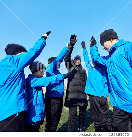 Team Motivation. Football players, young athletes and coach celebrating success with high-fives on outdoor field. Unity and determination. 123865970