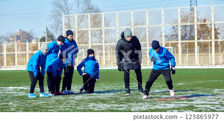 Young football player maneuvering ball through cones with focus, refining footwork during winter training. Pushing Boundaries. 123865977