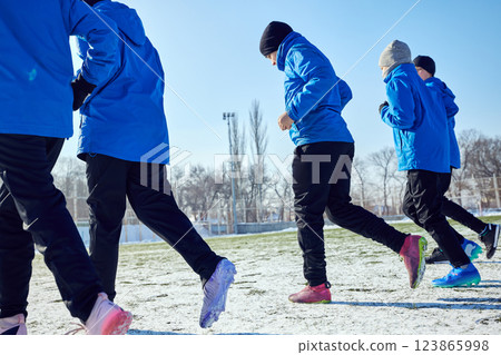 Speed and Coordination. Close-up of young footballers in synchronized motion, running together on snowy field. Speed and Coordination. Close-up of young footballers in synchronized motion, running together on snowy field. 123865998