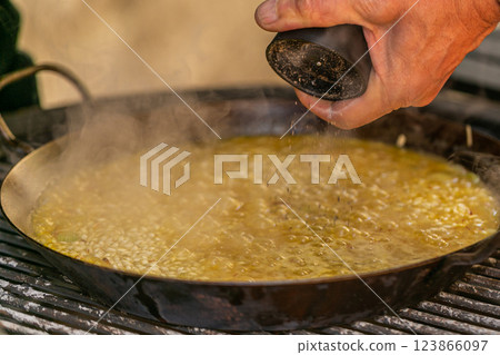 The chef prepares a traditional seafood paella on the grill. Traditional spanish dish. 123866097