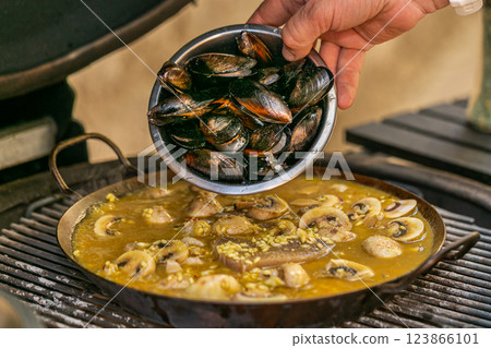 The chef prepares a traditional seafood paella on the grill. Traditional spanish dish. 123866101