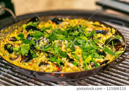 The chef prepares a traditional seafood paella on the grill. Traditional spanish dish. The chef prepares a traditional seafood paella on the grill. Traditional spanish dish. 123866110