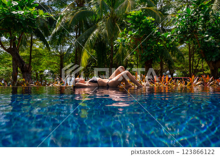 Enjoy a delightful experience of relaxing in a tropical pool surrounded by swaying palm trees 123866122