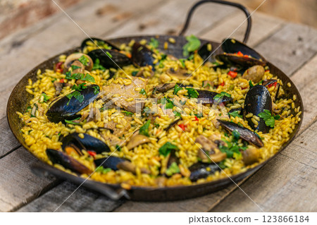 The chef prepares a traditional seafood paella on the grill. Traditional spanish dish. The chef prepares a traditional seafood paella on the grill. Traditional spanish dish. 123866184