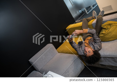 Curly-haired young man looking excited while playing video games during the break at work 123866565