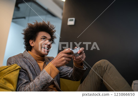 Dark-skinned man playing video games and looking involved Dark-skinned man playing video games and looking involved 123866650