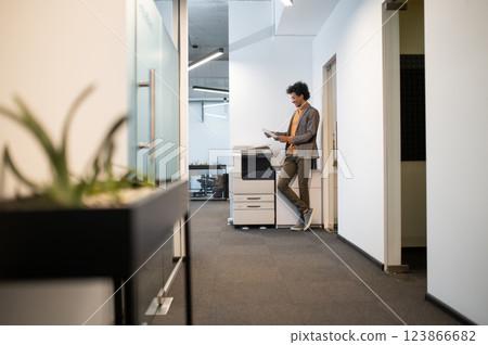 Curly-haired man standing the xerox in the office 123866682