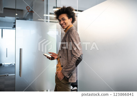 Confident curly-haired young businessman in the office Confident curly-haired young businessman in the office 123866841