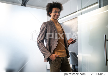 Confident curly-haired young businessman in the office Confident curly-haired young businessman in the office 123866842