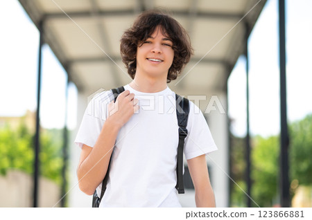 Dark-haired teenager in casual clothes spending time after school and looking contented Dark-haired teenager in casual clothes spending time after school and looking contented 123866881
