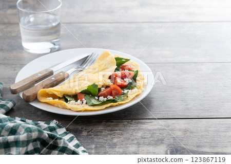 Stuffed omelette with tomatoes and spinach on wooden table Stuffed omelette with tomatoes and spinach on wooden table 123867119