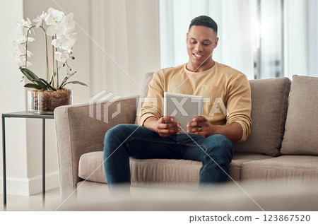 Man, tablet and social media on sofa in home, internet surfing or web browsing. Happy, relax and male from India on digital tech, mobile app or streaming content, movie or online video in house alone Man, tablet and social media on sofa in home, internet surfing or web browsing. Happy, relax and male from India on digital tech, mobile app or streaming content, movie or online video in house alone 123867520
