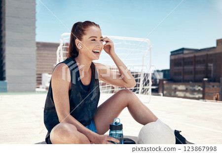 City sports, fitness and woman sitting to relax with water, ball and earbuds. Workout, rest and happy rooftop exercise, fun with urban soccer training and music streaming app in headphones in summer. 123867998