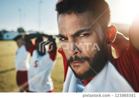 Face, soccer and stretching with a sports man getting ready for a game on a grass pitch or field with his team. Fitness, football and exercise with a sport group getting ready for a workout or match 123868381