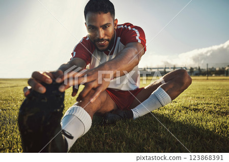 Fitness, man and stretching leg on grass in nature ready for exercise or football game. Health, wellness and young male from India warm up, stretch or prepare for workout, soccer or training outdoors 123868391