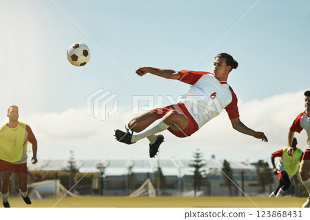 Soccer, game and man kicking a ball during training with the team on a field for sports. Athlete football player in the air to jump for a goal while playing in a professional match or competition Soccer, game and man kicking a ball during training with the team on a field for sports. Athlete football player in the air to jump for a goal while playing in a professional match or competition 123868431