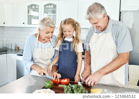 Grandparents, girl child in kitchen and cooking healthy food with vegetables on cutting board for happy family lunch at home. Natural, organic nutrition and clean diet for senior people in retirement 123868532