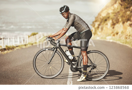 Cycling, energy and bike cyclist in a road along a mountain, power, focus and mindset in South Africa. Sports, fitness and marathon training with black man riding along views of the city on a bicycle 123868568