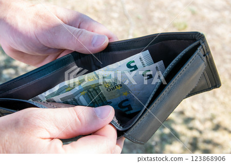 Man on the street and holding black leader partmone with euro money in the hands. Bills in the wallet for commerce concept. 123868906