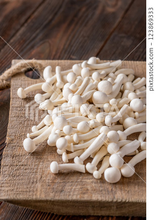 Fresh white beech mushrooms elegantly arranged on a rustic cutting board 123869333