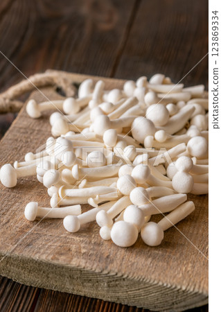Fresh white beech mushrooms elegantly arranged on a rustic cutting board Fresh white beech mushrooms elegantly arranged on a rustic cutting board 123869334