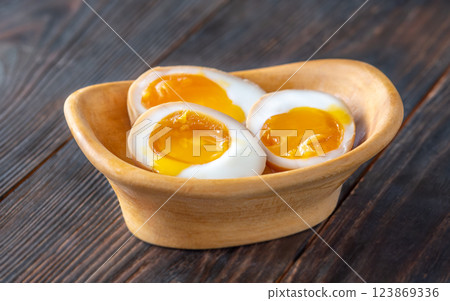Halved ajitsuke tamago ramen eggs with golden yolks in wooden bowl Halved ajitsuke tamago ramen eggs with golden yolks in wooden bowl 123869336