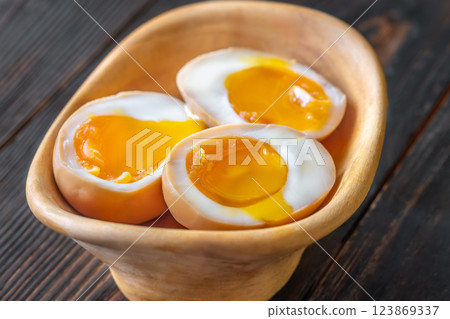Halved ajitsuke tamago ramen eggs with golden yolks in wooden bowl Halved ajitsuke tamago ramen eggs with golden yolks in wooden bowl 123869337
