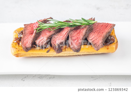 Grilled ciabatta sandwich with melted cheese, juicy steak, caramelized onions, and rosemary 123869342