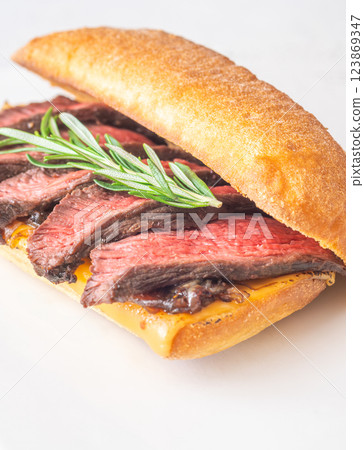 Grilled ciabatta sandwich with melted cheese, juicy steak, caramelized onions, and rosemary 123869347