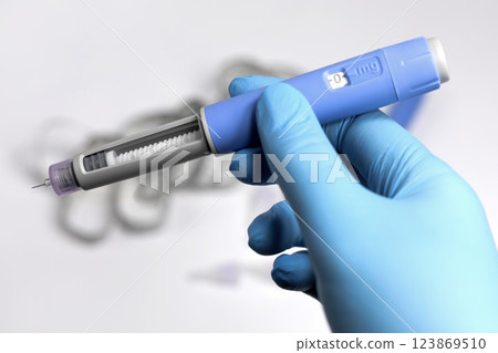 Hands in surgical gloves holding Ozempic Insulin injection pen for diabetics. Hands in surgical gloves holding Ozempic Insulin injection pen for diabetics. 123869510