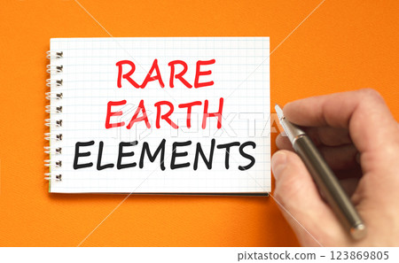 Rare earth elements symbol. Concept words Rare earth elements on beautiful white note. Beautiful orange background. Businessman hand with pen. Business and rare earth elements concept. Copy space. 123869805