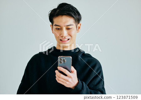 一名20多歲的年輕人正在操作智慧型手機 一名20多歲的年輕人正在操作智慧型手機 123871509