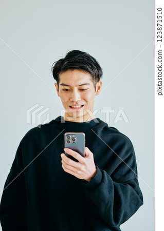 A young man in his twenties operating a smartphone A young man in his twenties operating a smartphone 123871510