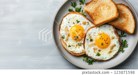 Two fried eggs with fried onions served on plate with toasted bread and parsley garnish 123871598