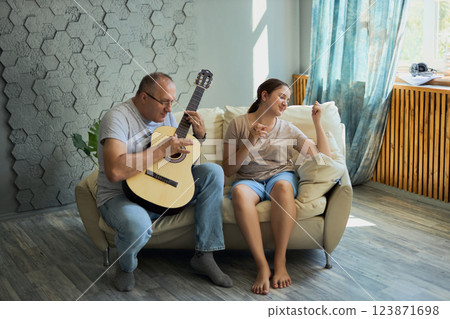 Grandfather and granddaughter sing and play guitar 123871698