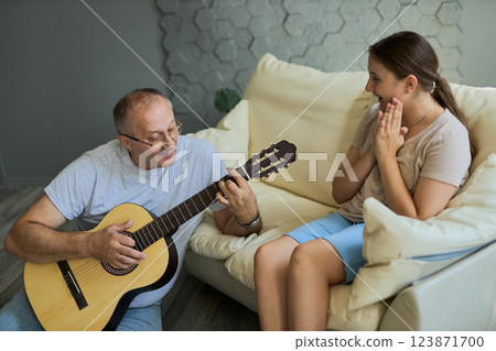 Grandfather and granddaughter sing and play guitar Grandfather and granddaughter sing and play guitar 123871700