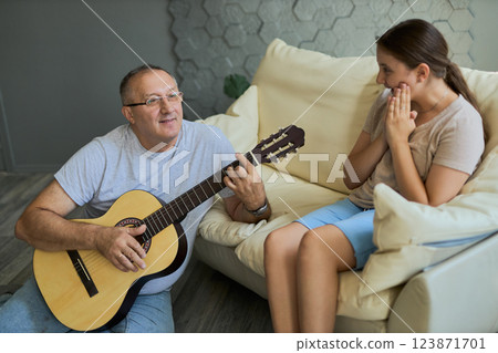 Grandfather and granddaughter sing and play guitar Grandfather and granddaughter sing and play guitar 123871701