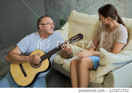 Grandfather and granddaughter sing and play guitar Grandfather and granddaughter sing and play guitar 123871702