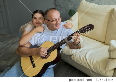 Grandfather and granddaughter sing and play guitar 123871706