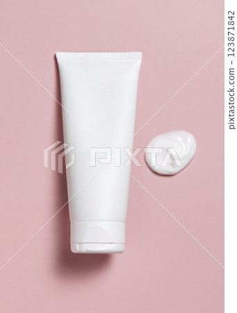 White blank squeeze cosmetic tube near cream smear on light pink top view, mockup White blank squeeze cosmetic tube near cream smear on light pink top view, mockup 123871842