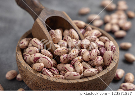Wooden bowl full of dried pinto beans with scoop on gray closeup. Traditional Latin American legumes Wooden bowl full of dried pinto beans with scoop on gray closeup. Traditional Latin American legumes 123871857