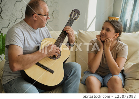 Grandfather and granddaughter sing and play guitar 123872098