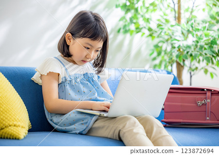 Elementary school student using a computer in the living room Elementary school student using a computer in the living room 123872694