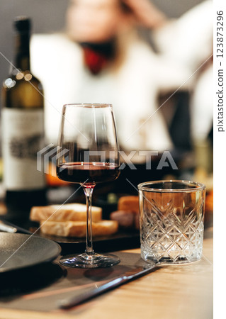 Glass of rich red wine served with cheese plate and fruits on dark wooden background. Appetizers table with wine glasses, rustic style table setting in winery 123873296